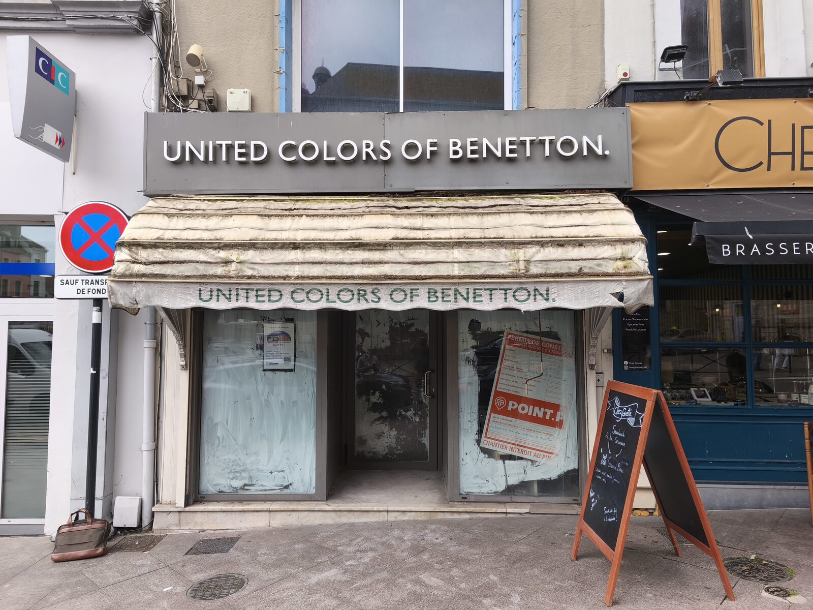 Avant : la devanture de l'ancienne boutique de prêt-à-porter, avec bandeau gris et store corbeille délavé