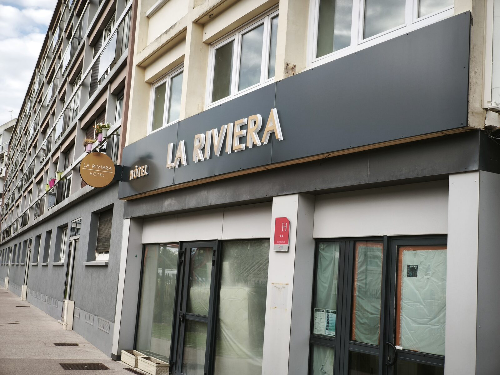 Hôtel La Riviera — bandeau de façade et enseigne drapeau ronde